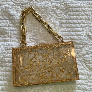 Never used. Can’t fit my glasses case in it. Clear w/gold specks clutch w/handle